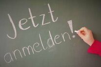 Mit Kreide auf Tafel geschrieben: "Jetzt anmelden!"