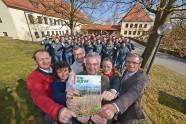 Studierende und Lehrer vor Schulgebäude, Lehrer halten gemeinsam Magazin topagrar in Händen